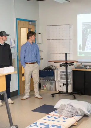 Students display their prototype of a collapsible camping bed