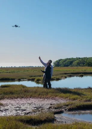 Johanna Birchem with Will Kotchtitzky flying a drone on the marsh.