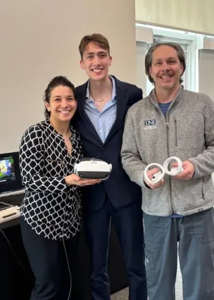 A student and UNE staff pose with a VR headset