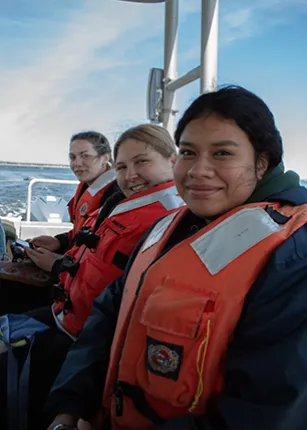 Three U N E students ride a boat on their way to Ram Island