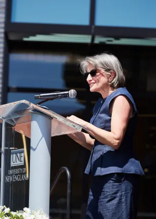 UNE COM Dean Jane Carreiro smiles speaks at the podium
