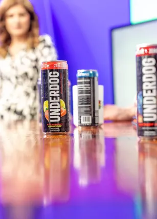 A lineup of Underdog Performance Drinks and Greenlight Maine coffee mugs