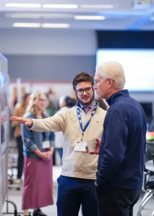 student explains research to student at research symposium