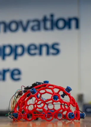 A red skull cap with electronic sensors sits on a table in the Makerspace.