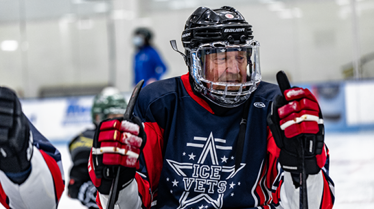 A man smiles as he participates in an adaptive sled hockey demonstration