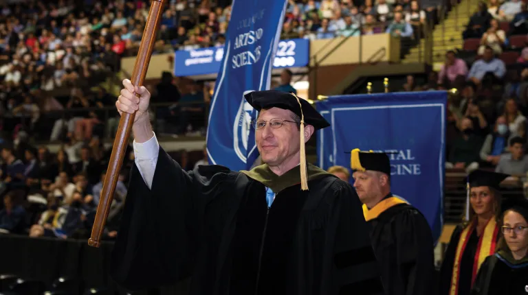 A U N E faculty member leads the procession at graduation