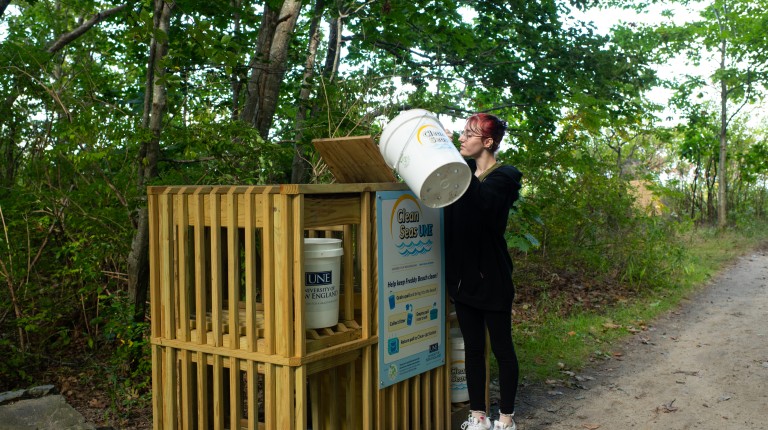 A student empties a pail of rubbish from a beach clean up at the new Clean Seas UNE kiosk