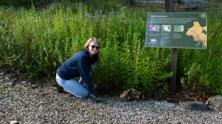 A student tends to UNE's rain gardens