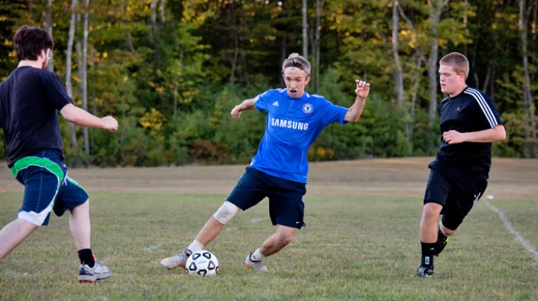 Three U N E students playing intramural soccer