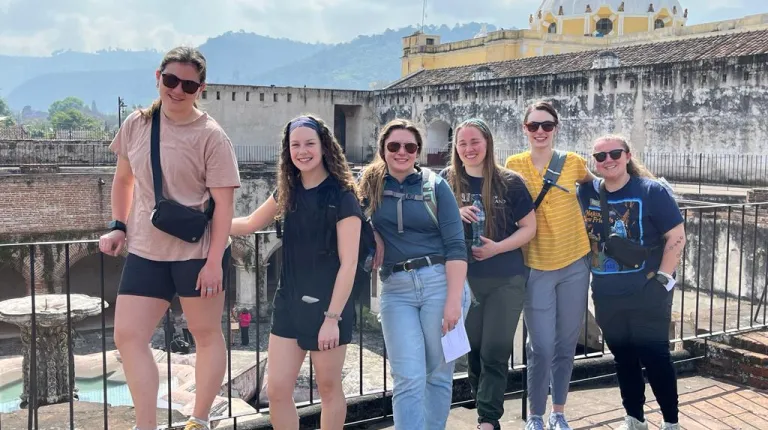 The group of students poses in front of local scenery in Guatemala