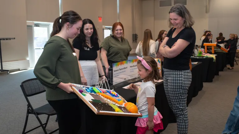 A child plays with an adaptive toy at a display table