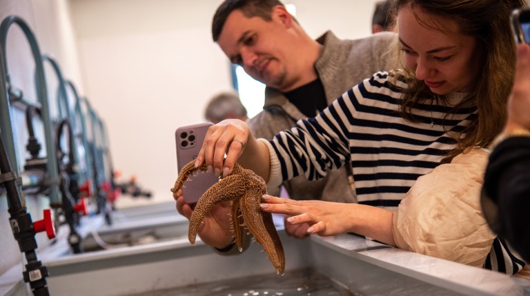A member of the delegation holds a starfish in UNE's Marine Science Center