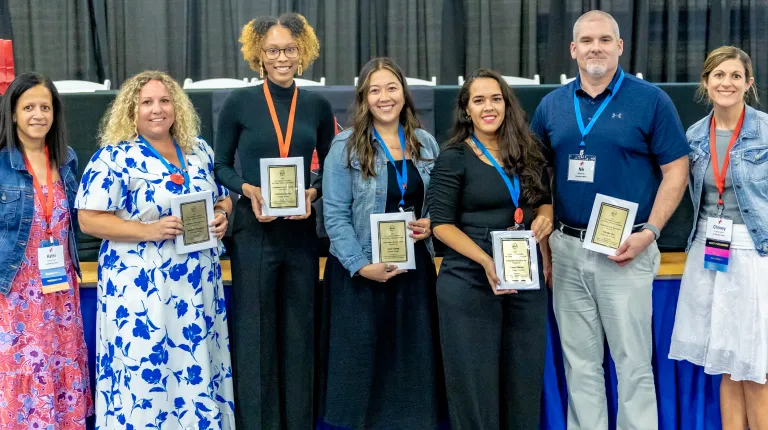 Conference attendees hold various awards they won at the three-day event