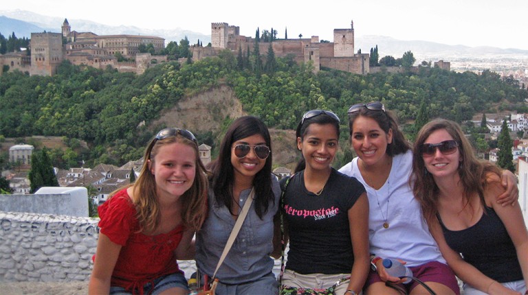 A group of students sitting in front of a cityscape in Spain