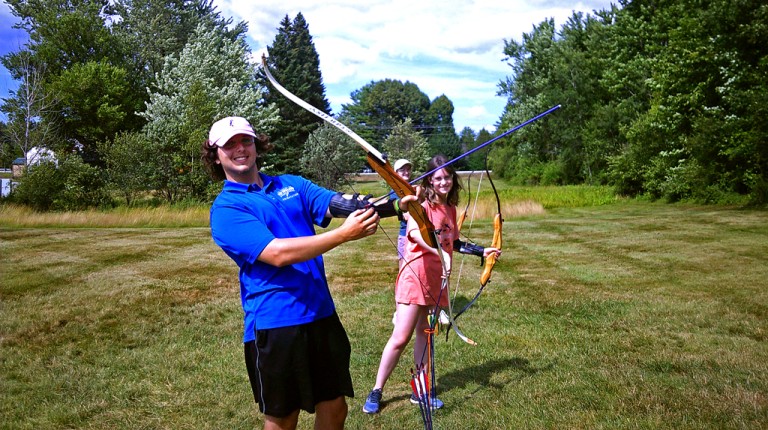 Two students hold up bows for an LL Bean discovery class on archery