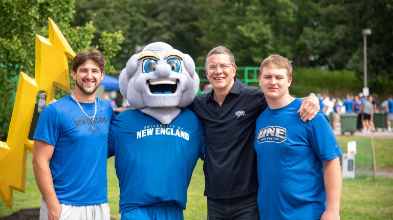 President Herbert poses with students and UNE's mascot, Stormin' Norman