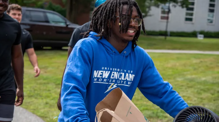A student moves belongings across the quad