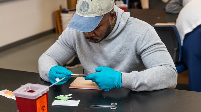 A C O M student practices suturing on a pig's foot