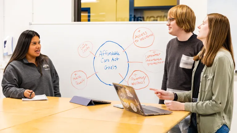 Three students discussing health law in the Makerspace