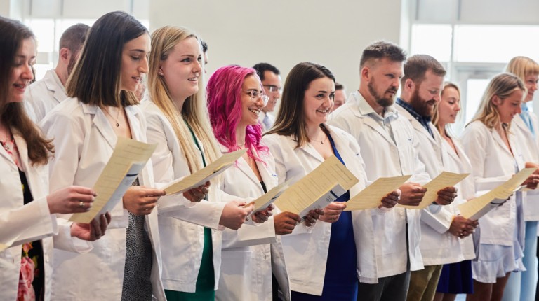 A row of P A students in their white coats recite an oath