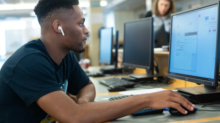 A student uses the computer in the Biddeford Campus library