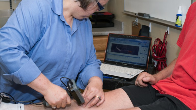 Professor Rudolph using a lab tool on a patient's knee