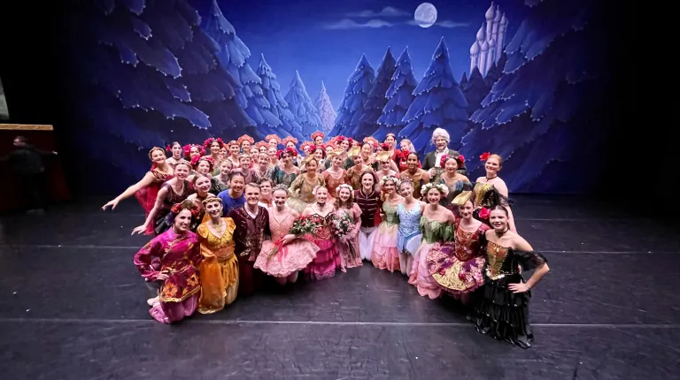 A cast of ballet dancers pose in costumes from "The Nutcracker"