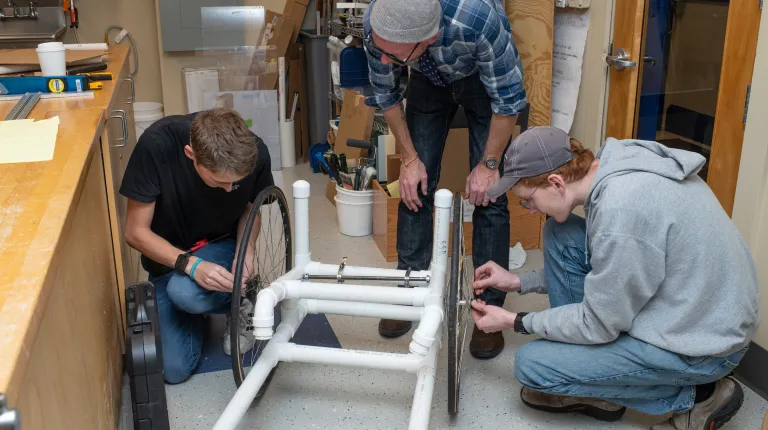 group of students and professor working on building wheelchair
