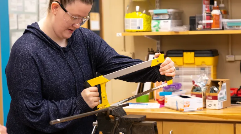 student using saw tool in the makerspace