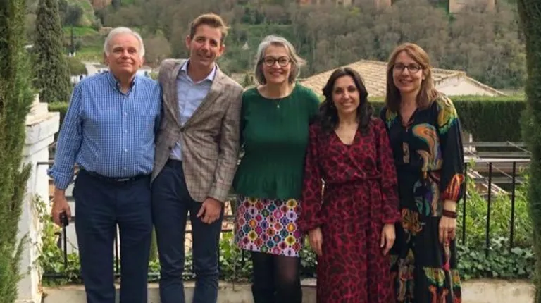 A group of people poses in front of a Spanish garden