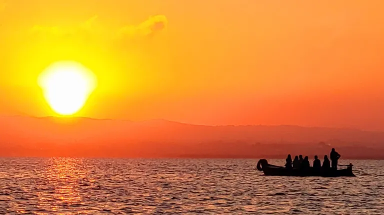 The ocean with the setting sun and a boat