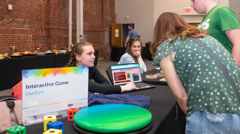 Members of the public interact with UNE students at a table