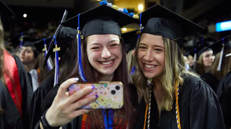 Two graduates take a selfie with a smartphone