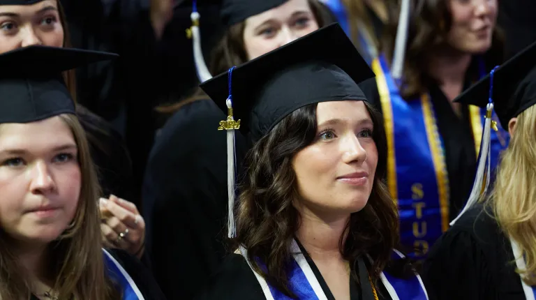 A graduate watches the ceremony from her seat
