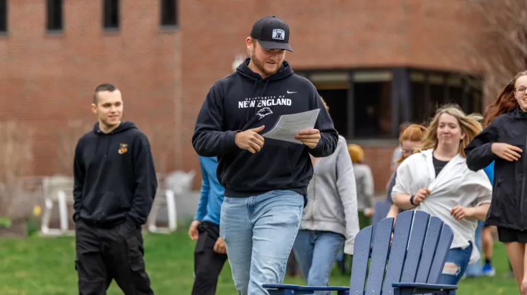 A UNE student reads instructions to a group of high school students