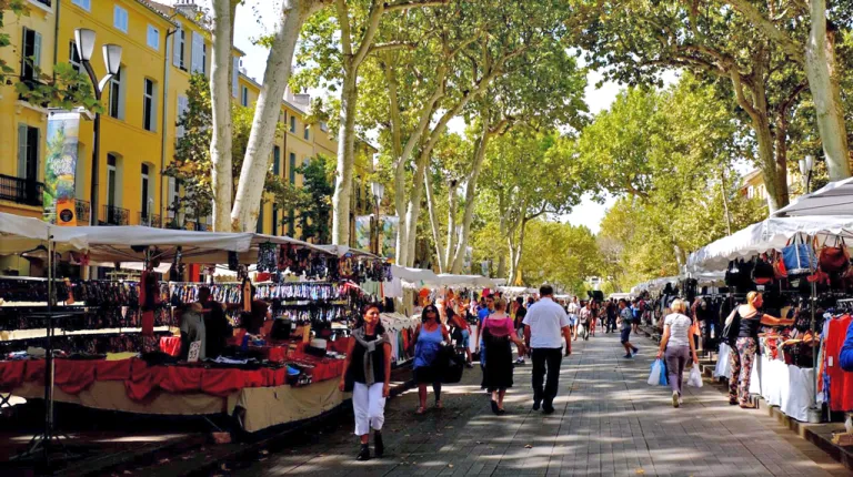 Several people stroll through a street lined with market stalls