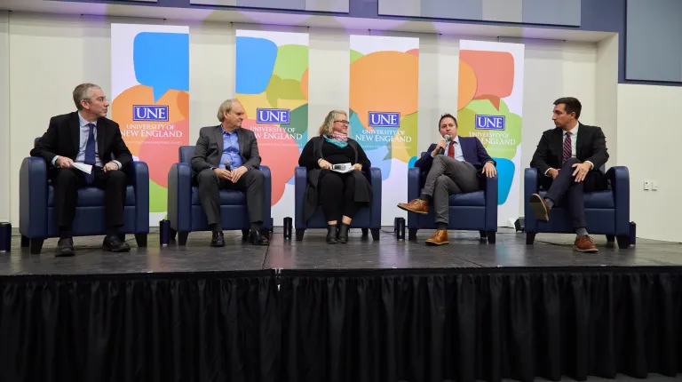 Four panelists and a moderator gather onstage