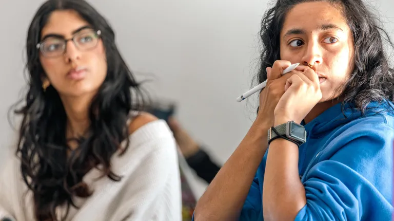 Two students listen to classroom conversation