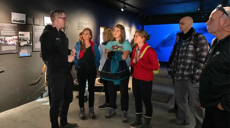 A group of students listen to a guide in a whale museum