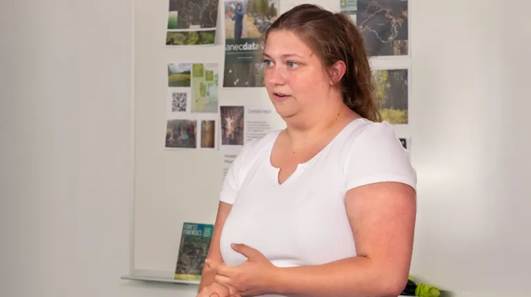 A sustainability fellow presenting in front of a group of images of forests