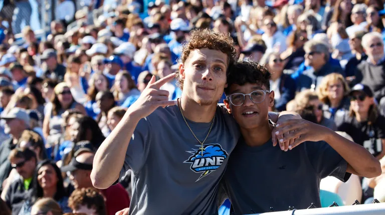 Two students pose for a photo in the stands at Homecoming