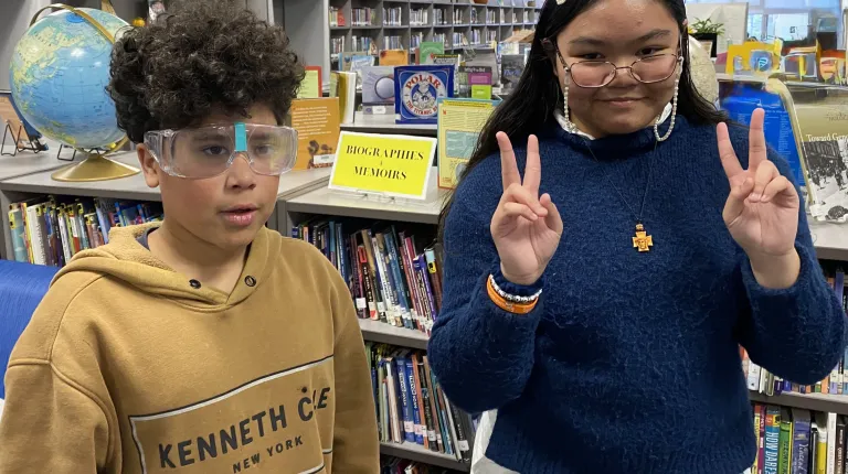 Two children pose for photos in the Saco Middle School library