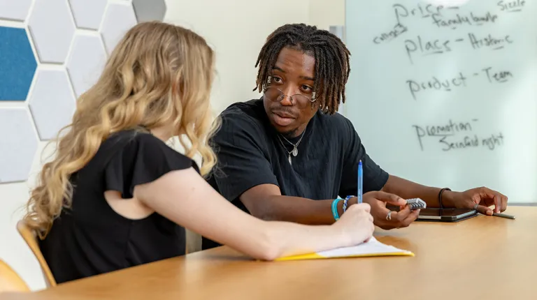 Two business students talk in a classroom