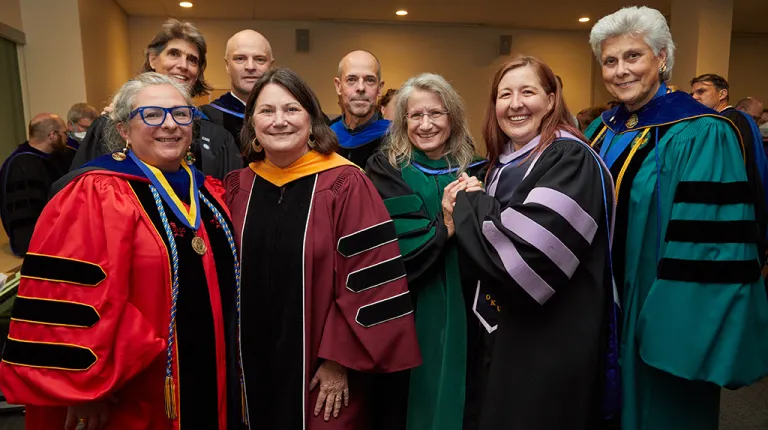 A group of U N E faculty members pose in regalia