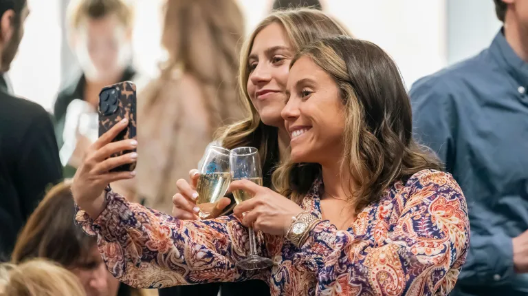 Two students take a selfie while toasting glasses