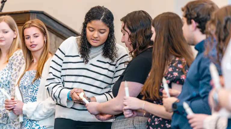 A student 'lights' another's candle as part of the induction ceremony