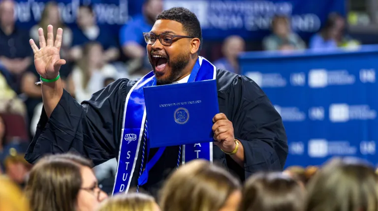 A graduate cheers after receiving their diploma