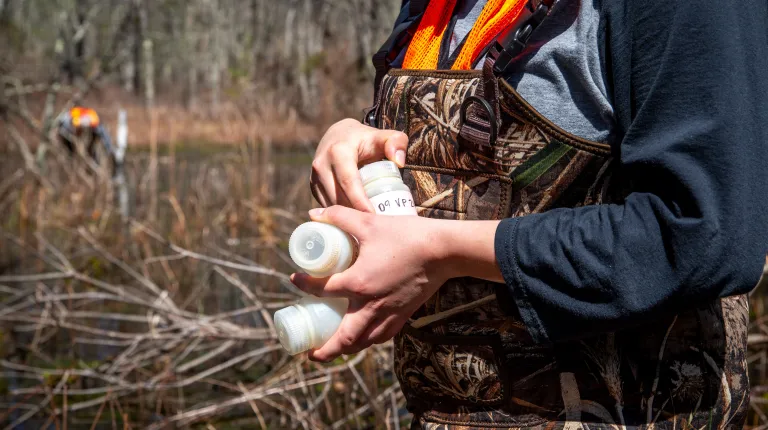 A student holds bottles for sampling water quality