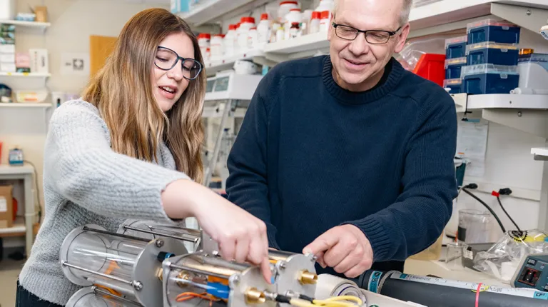 A student works with a professor on a tool for testing ocean water