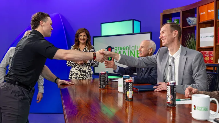 The two UNE entrepreneurs shake the judges' hands